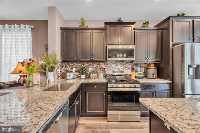 a kitchen with stainless steel appliances granite countertop a sink stove and refrigerator