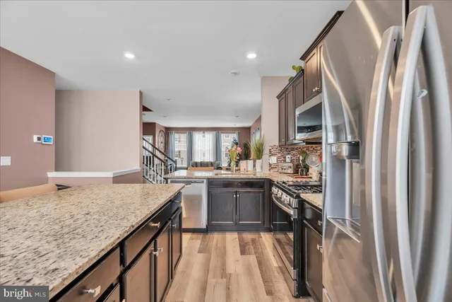 a kitchen with stainless steel appliances granite countertop sink stove refrigerator and cabinets
