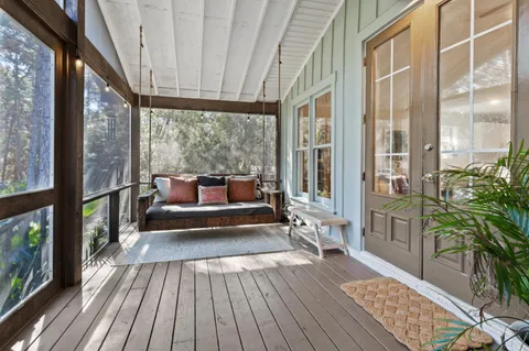 a living room with couches and balcony with wooden floor