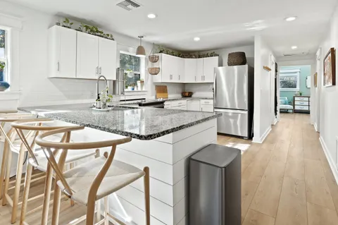 a kitchen with stainless steel appliances granite countertop a refrigerator a stove a sink dishwasher and white countertops with wooden floor