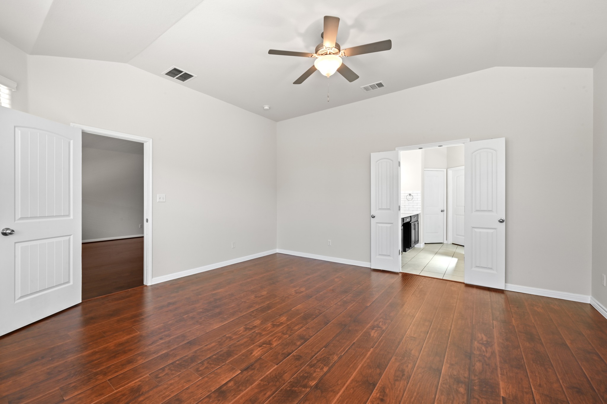351 Wincliff Drive Buda, TX 78610 - Photo 22 of 40 Rich hardwood flooring stretches across this naturally illuminated bedroom with a vaulted ceiling and modern ceiling fan.