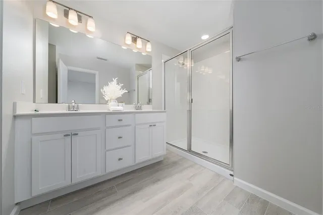 a bathroom with a double vanity sink a toilet a mirror and shower