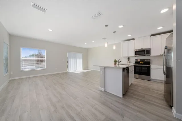 a view of kitchen with refrigerator stove and wooden floor