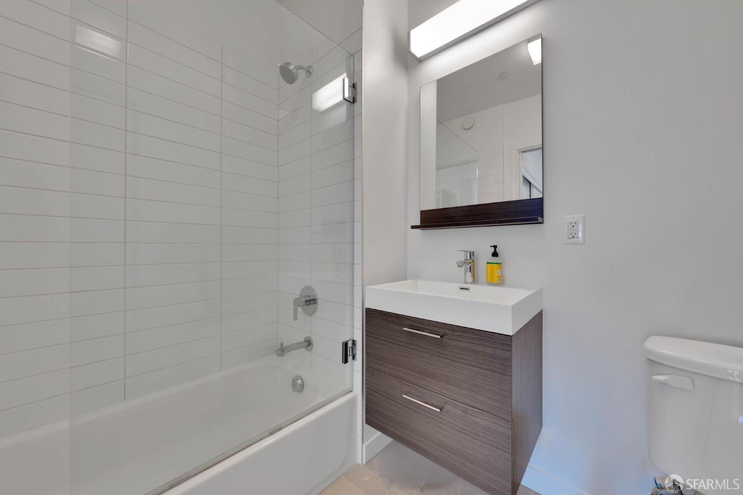 870 Harrison Street, Unit 302 San Francisco, CA 94107 - Photo 23 of 41 a bathroom with a bathtub sink vanity and mirror