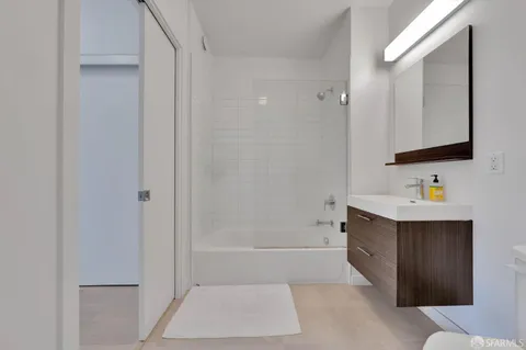 a bathroom with a tub sink vanity and mirror