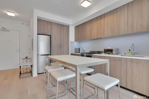 a room with a table chairs refrigerator and cabinets