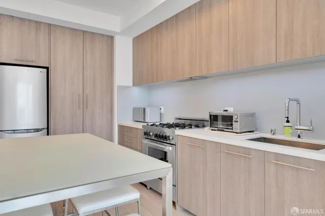 a kitchen with stainless steel appliances a stove a refrigerator a sink and white cabinets