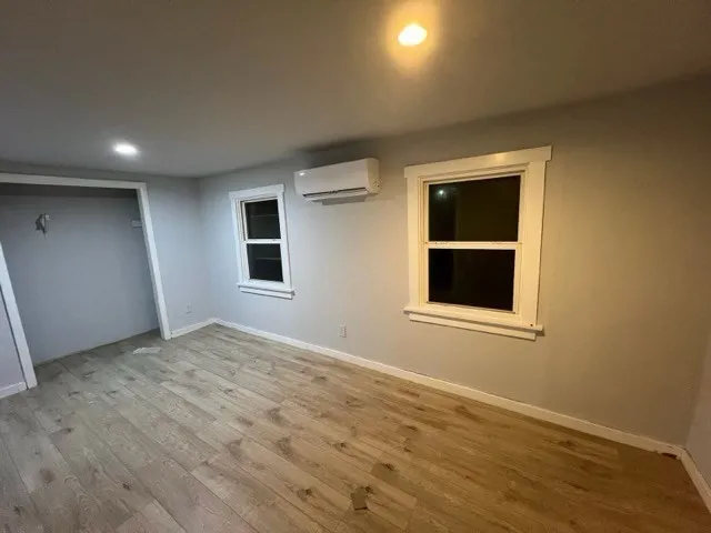a view of an empty room with window and wooden floor