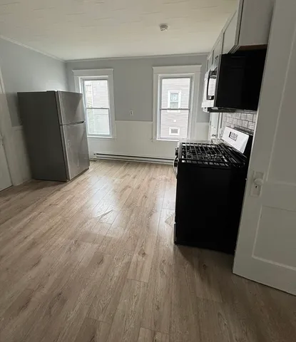 an empty room with wooden floor cabinet and a window