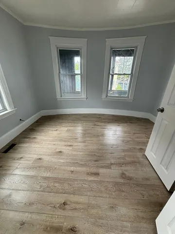 a view of an empty room with window and wooden floor
