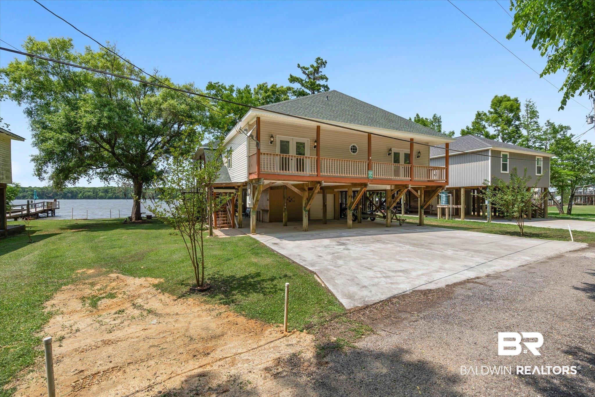 41923 Bayou Road Bay Minette, AL 36507 - Photo 31 of 35 Elevated residence featuring a covered balcony with a white railing, a concrete driveway, and a verdant lawn