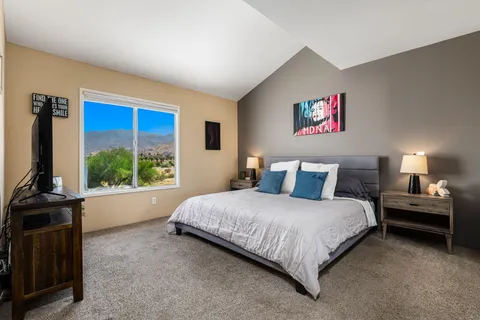 a bedroom with bed and a flat tv screen on dresser