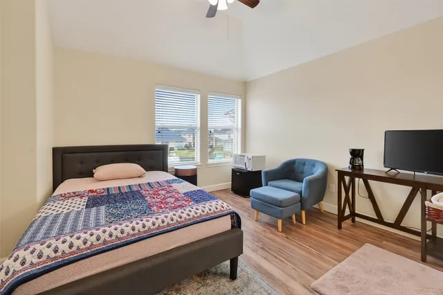 a bedroom with a bed a chair and a potted plant on the dresser
