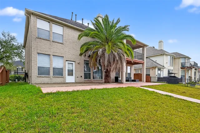front view of a house with a yard and palm trees