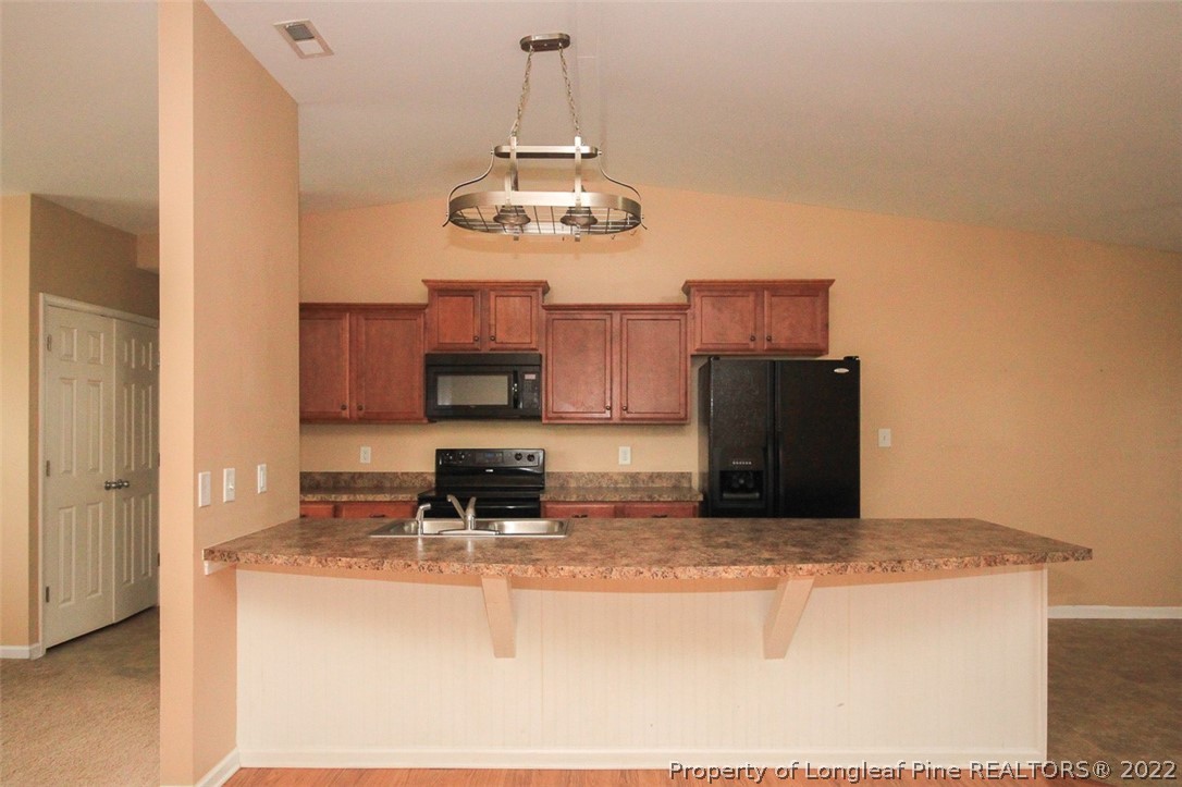 6377 Overhills Road Spring Lake, NC 28390 - Photo 10 of 29 a kitchen with kitchen island stainless steel appliances granite countertop a sink and a refrigerator