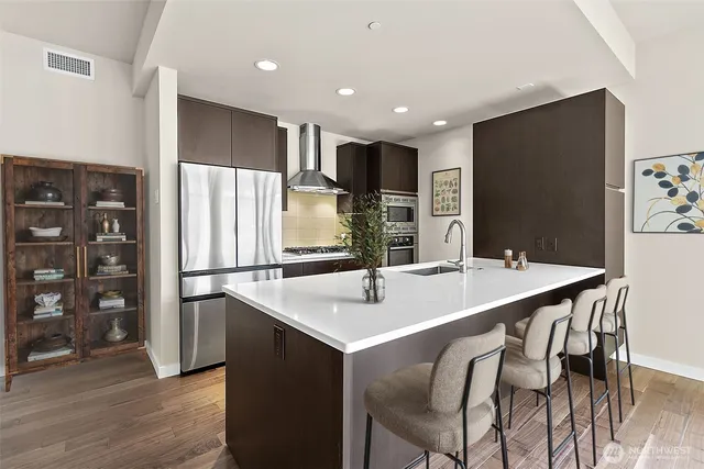 a kitchen with stainless steel appliances kitchen island granite countertop a sink and a refrigerator