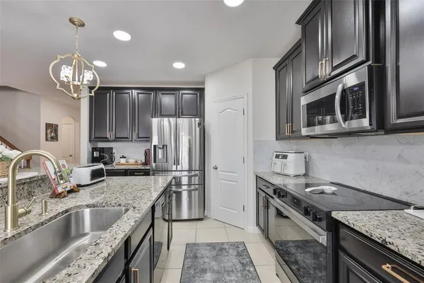 a kitchen with stainless steel appliances granite countertop a sink stove and refrigerator