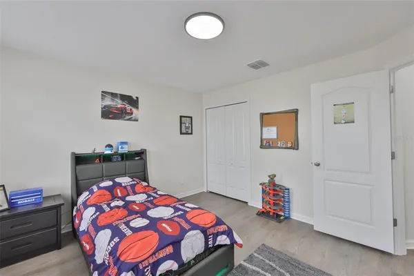 a bedroom with a bed and a lamp on dresser
