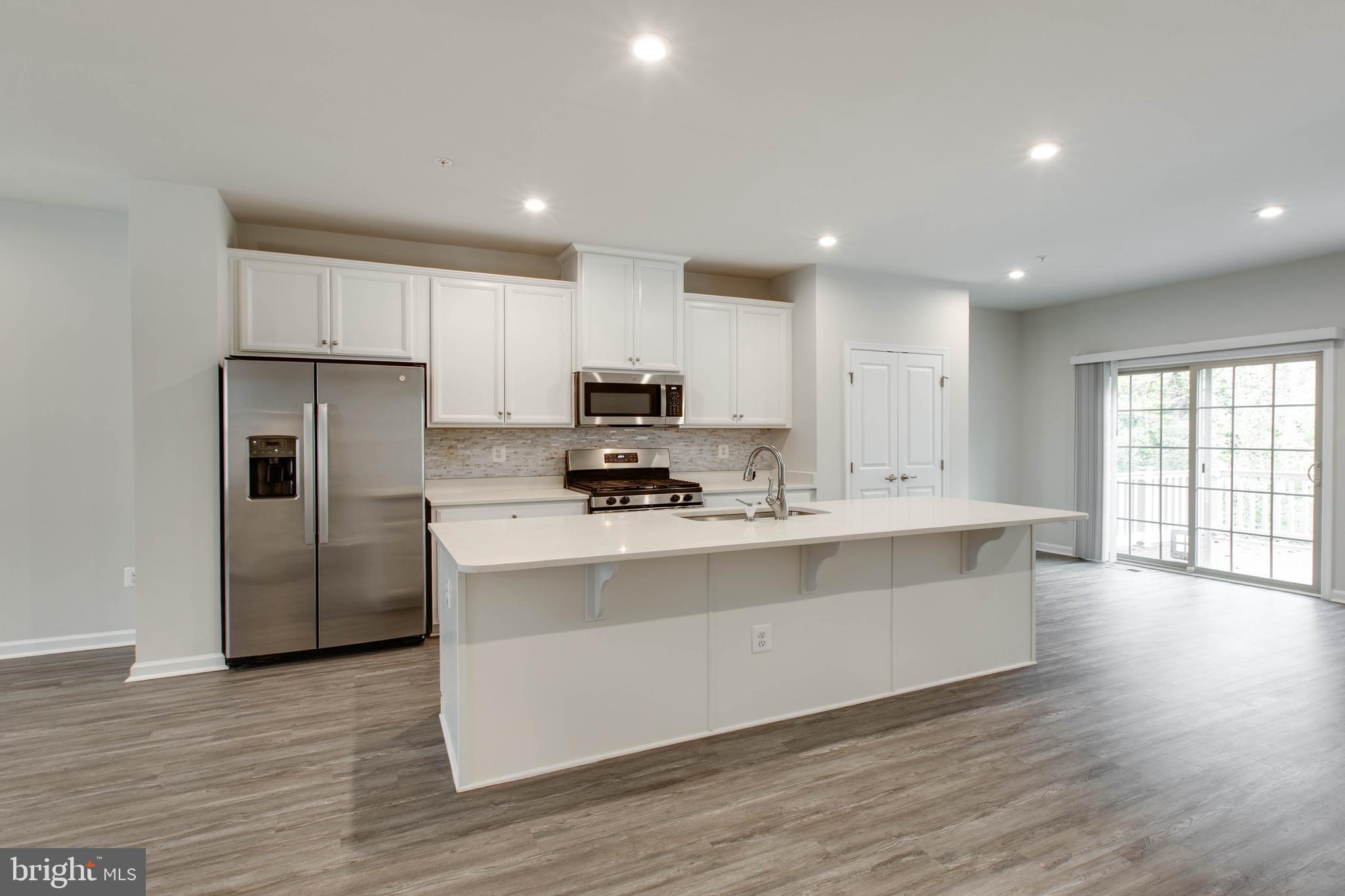 3004 Cornfield Avenue Hanover, MD 21076 - Photo 17 of 50 a kitchen with stainless steel appliances granite countertop a stove a sink a refrigerator and white cabinets with wooden floor