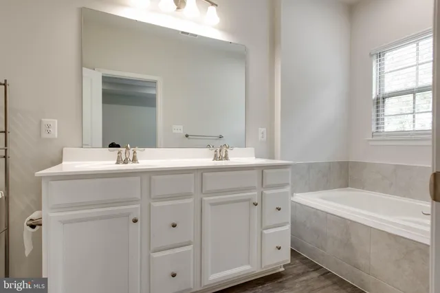 a bathroom with a tub a sink and mirror