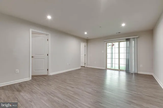 a view of an empty room with wooden floor and window