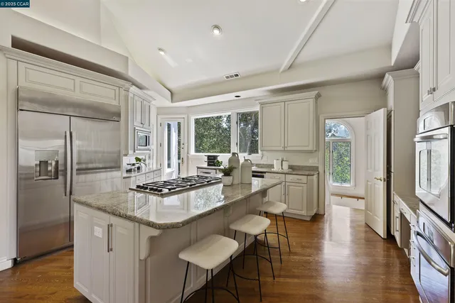 a kitchen with stainless steel appliances granite countertop a stove a sink and a white cabinets with wooden floor