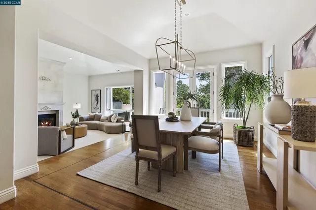 a dining room with wooden floor a chandelier a glass table and chairs