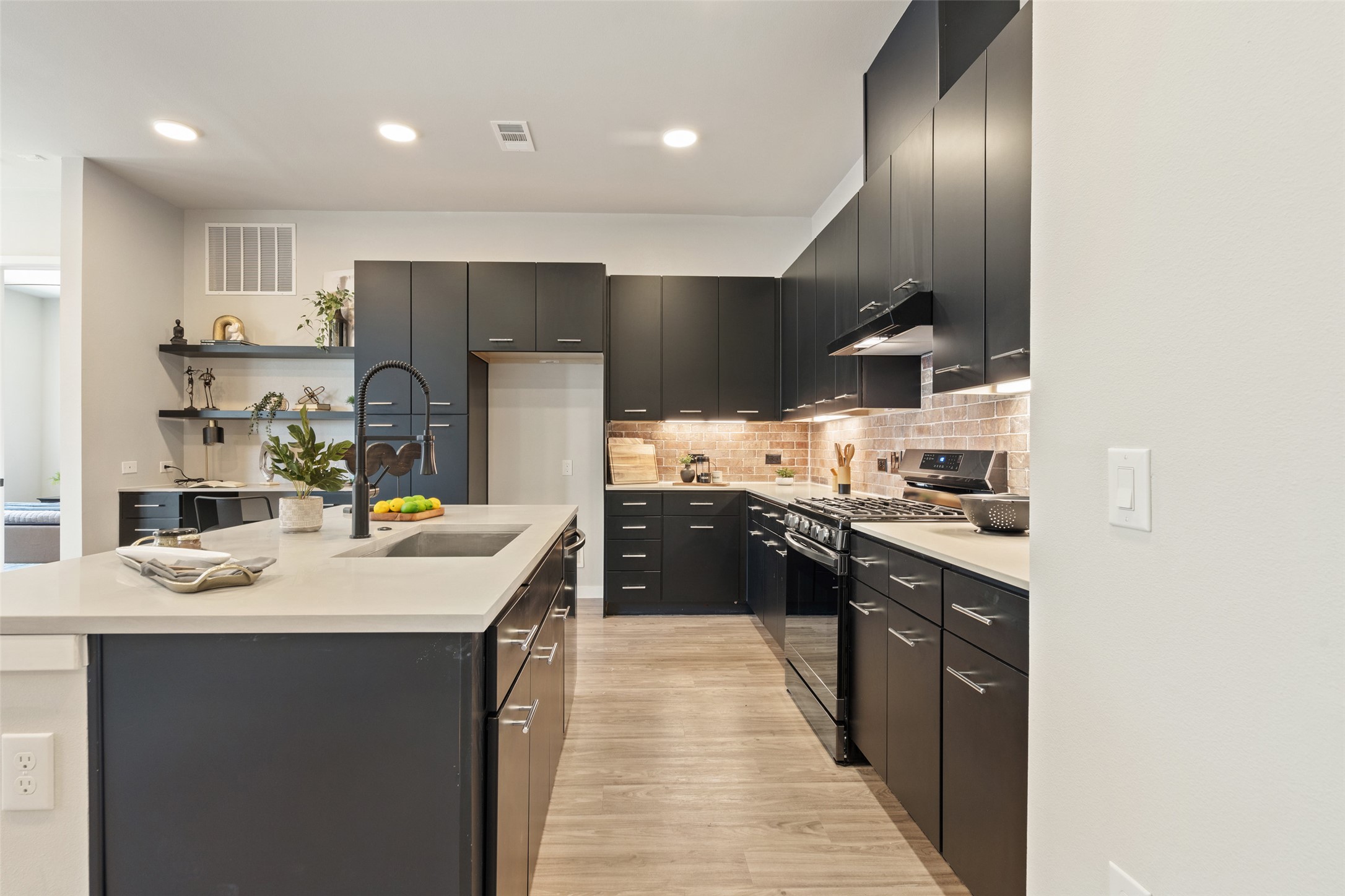 4510 Terry-O Lane, Unit 341 Austin, TX 78745 - Photo 7 of 40 The kitchen features dark cabinetry, a light-colored countertop on the island, and a sink with a black faucet