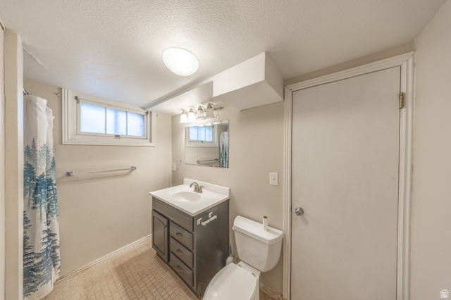 193 Locust Street Clearfield, UT 84015 - Photo 17 of 29 Bathroom featuring a dark wood-finish vanity with a white countertop and integrated sink, a mirrored medicine cabinet, and a multi-bulb vanity light fixture