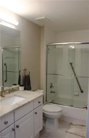 a bathroom with a granite countertop sink a toilet and shower