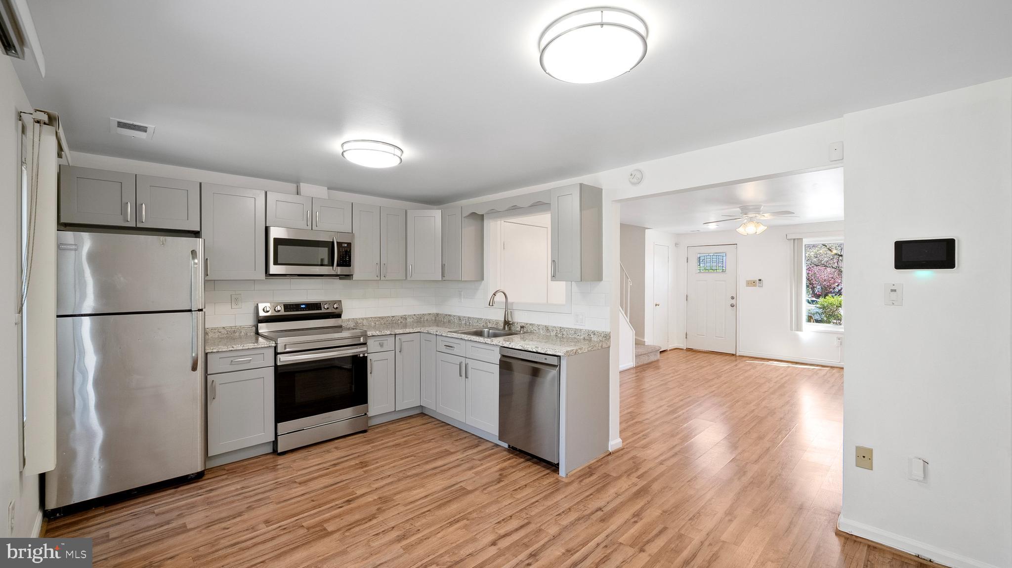 10710 Lester Street Silver Spring, MD 20902 - Photo 9 of 24 a kitchen with stainless steel appliances granite countertop a refrigerator a stove top oven a sink dishwasher and a refrigerator with wooden floor