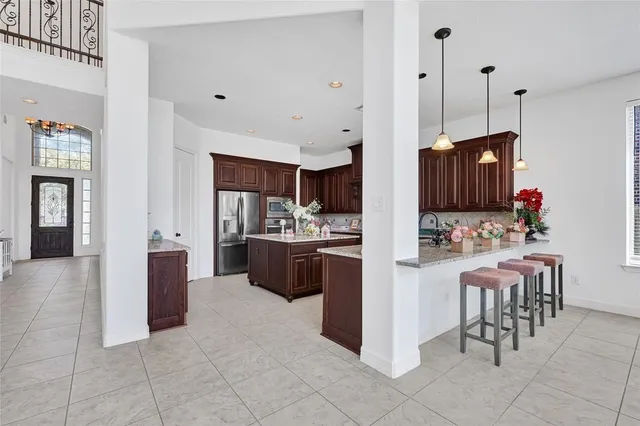 a kitchen with stainless steel appliances granite countertop a kitchen island a stove a refrigerator and a sink