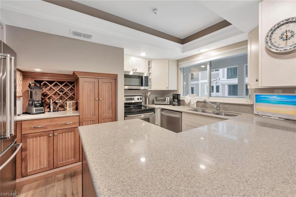 180 6th Avenue South, Unit 3 Naples, FL 34102 - Photo 12 of 44 a kitchen with stainless steel appliances a stove a refrigerator a sink a stove and white cabinets
