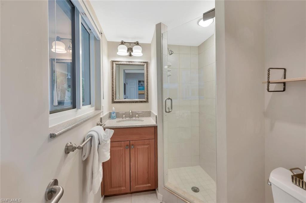 180 6th Avenue South, Unit 3 Naples, FL 34102 - Photo 21 of 44 a bathroom with a granite countertop sink a mirror and a bathtub