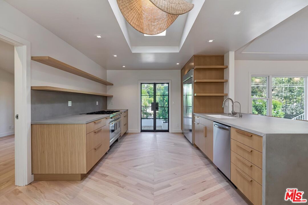 2203 Bowmont Drive Beverly Hills, CA 90210 - Photo 8 of 21 a large kitchen with stainless steel appliances a large counter top a stove a sink and a refrigerator