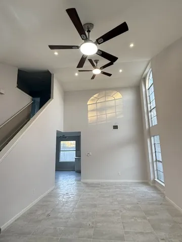 en empty room with windows and ceiling fan