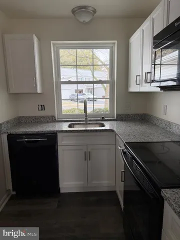 a kitchen with granite countertop a stove a sink and a microwave