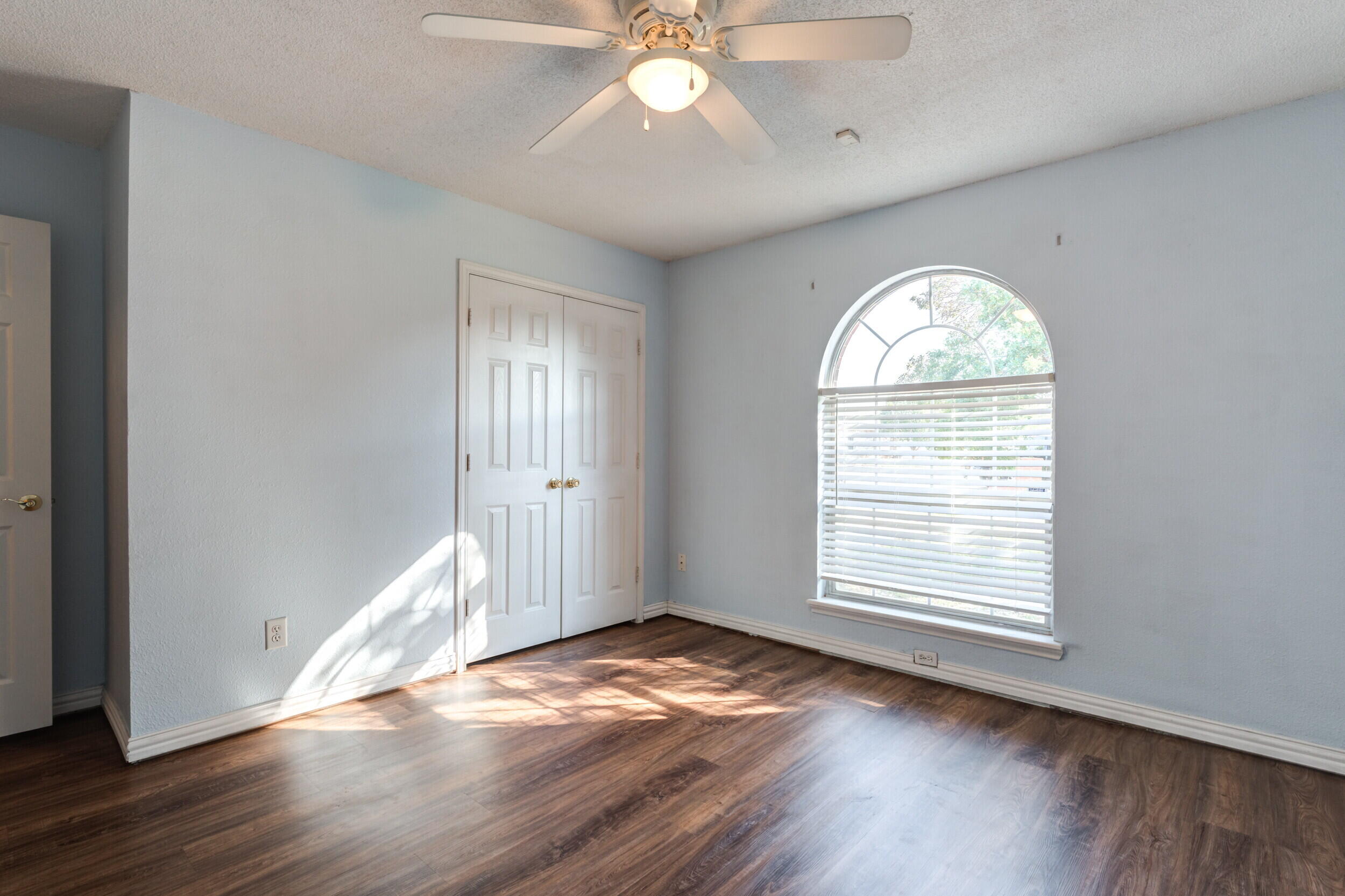 6325 14th Street Lubbock, TX 79416 - Photo 18 of 28 an empty room with wooden floor chandelier fan and windows