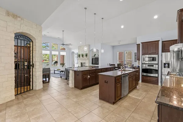 a large kitchen with stainless steel appliances kitchen island granite countertop wooden cabinets a sink dishwasher a stove and a refrigerator