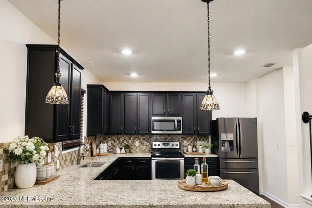a kitchen with stainless steel appliances kitchen island granite countertop a refrigerator and a stove top oven