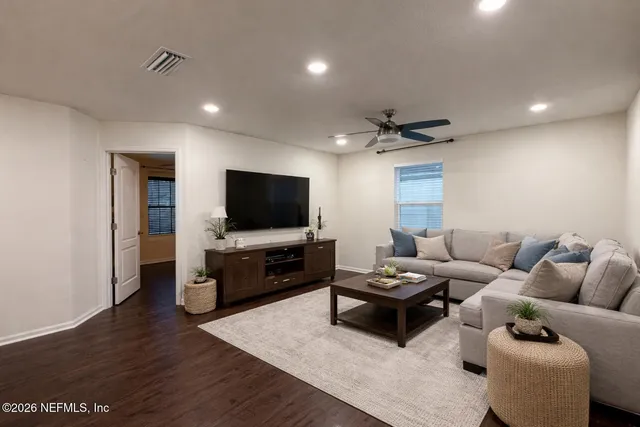 a living room with furniture a flat screen tv and kitchen view
