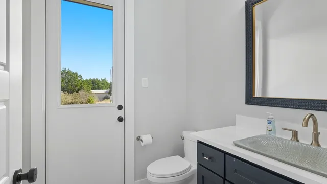 a bathroom with a granite countertop sink vanity mirror and toilet