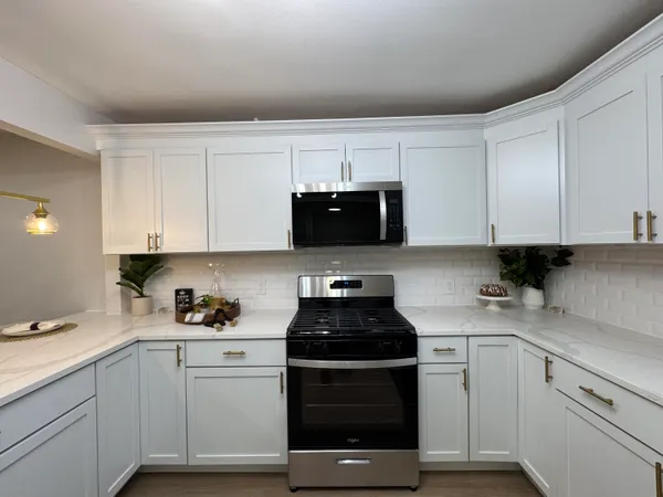 a kitchen with white cabinets and black appliances