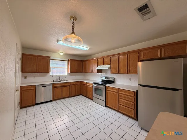 a kitchen with stainless steel appliances granite countertop a stove sink refrigerator and cabinets