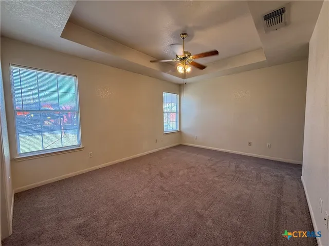 an empty room with windows and fan