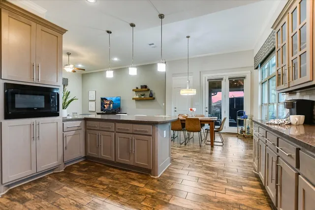 a kitchen with stainless steel appliances granite countertop a stove a sink a oven a dining table and chairs with wooden floor