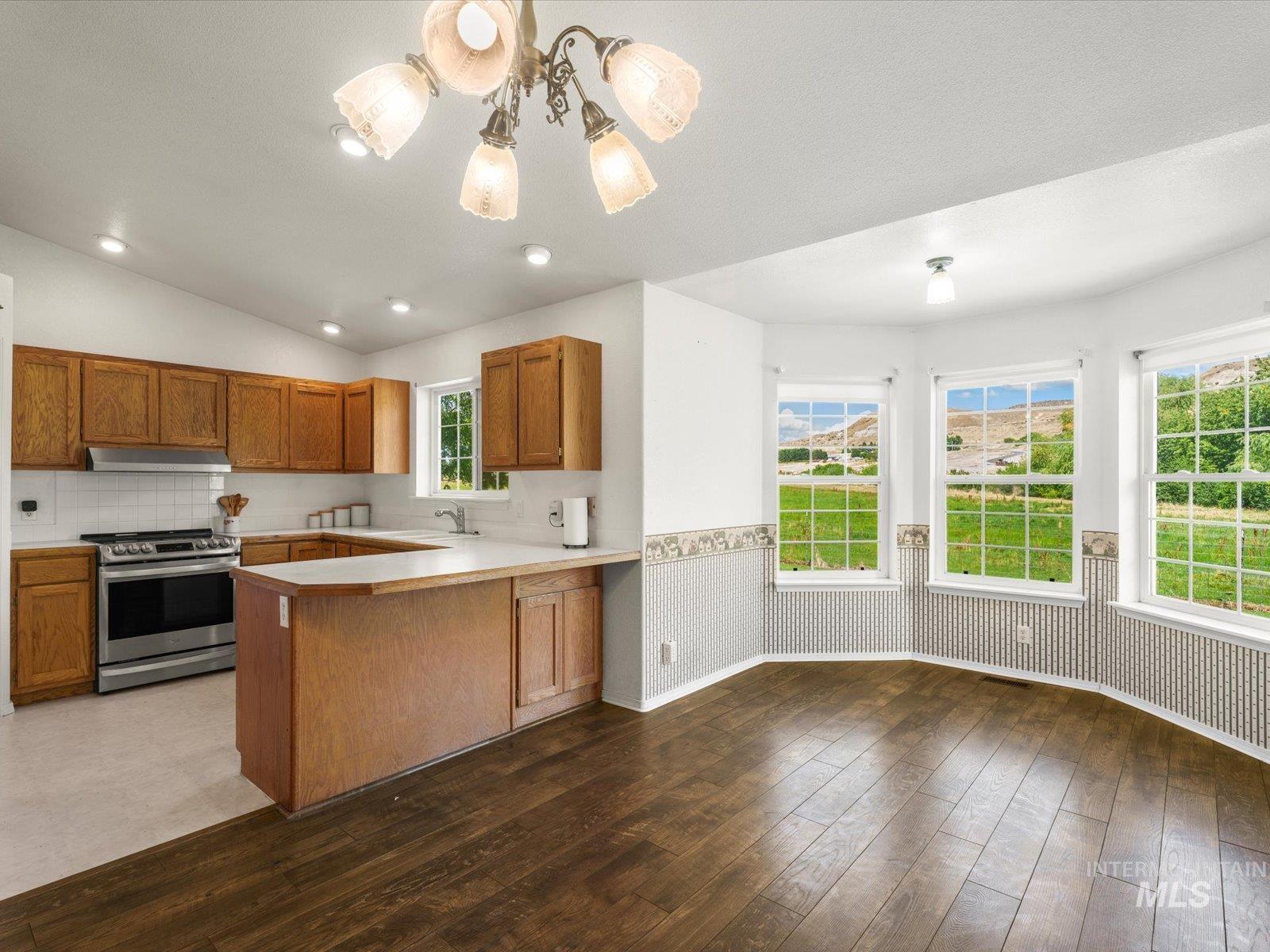 3540 Wills Road Emmett, ID 83617 - Photo 9 of 36 Open-concept kitchen and dining area featuring wood-finish flooring, a bay window with multiple panes, recessed lighting, and a kitchen island with seating