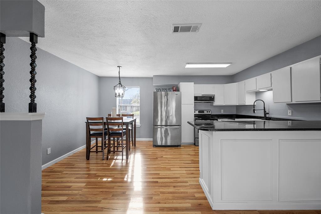 711 Rosedale Drive Hewitt, TX 76643 - Photo 5 of 16 a kitchen with stainless steel appliances granite countertop a stove top oven a refrigerator a dining table and chairs with wooden floor