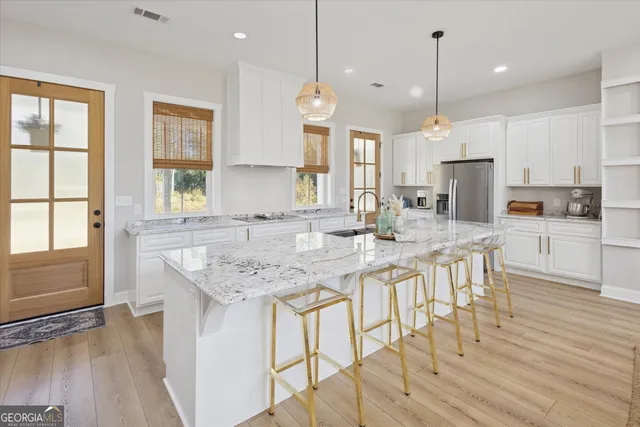 a kitchen with stainless steel appliances granite countertop a stove a sink refrigerator and a wooden floor