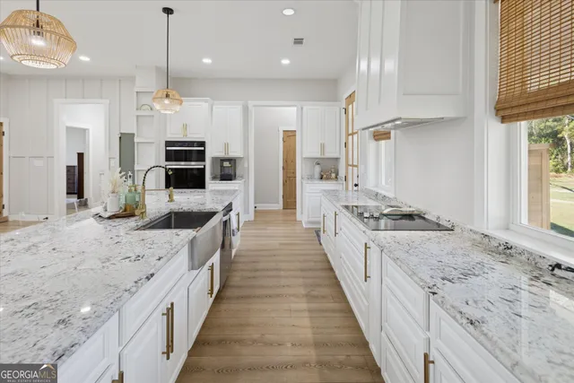 a large kitchen with stainless steel appliances kitchen island granite countertop a large counter top a stove a chimney a sink and a refrigerator